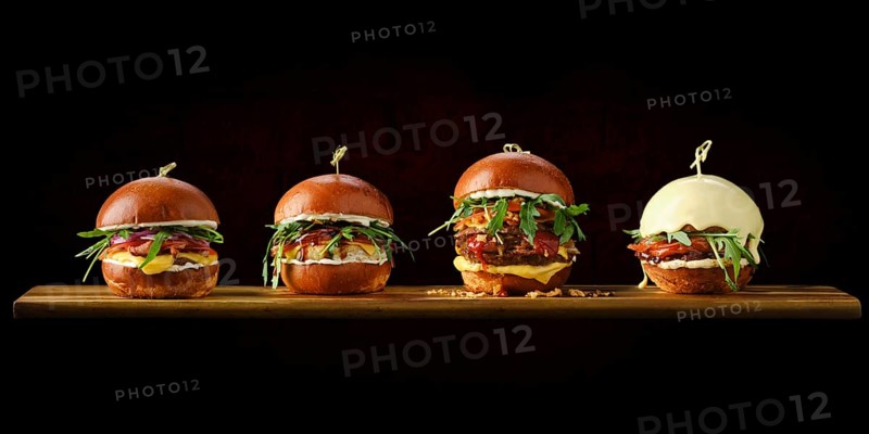 Set of four burgers with different types of meat on wooden serving board