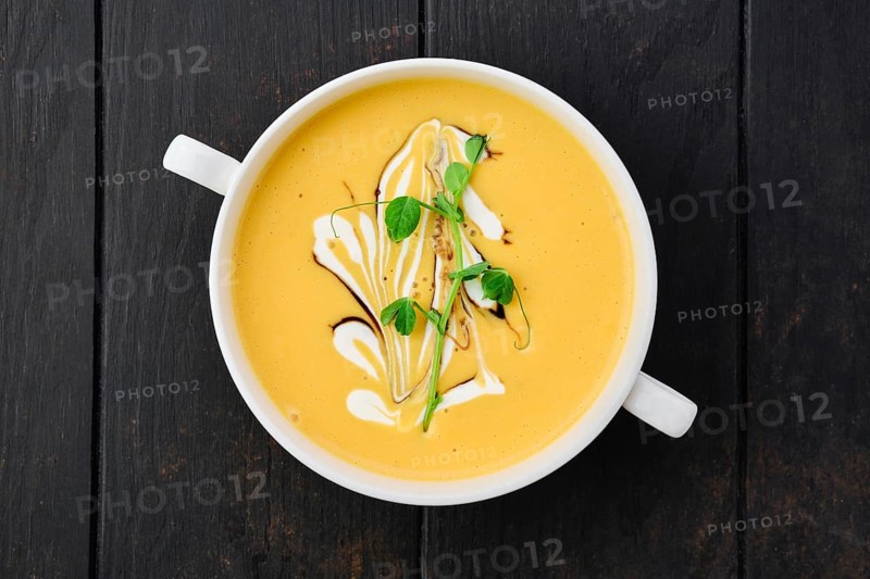 Top view of pumpkin puree soup with barbecue sauce and sour cream