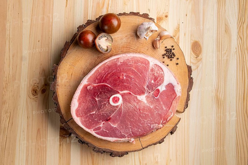 Piece of raw pork ham cut on wooden cutting board