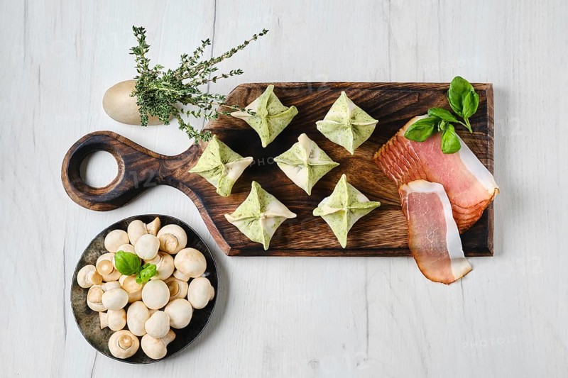 Top view of dumplings stuffed with smoked ham and mushrooms on wooden serving board