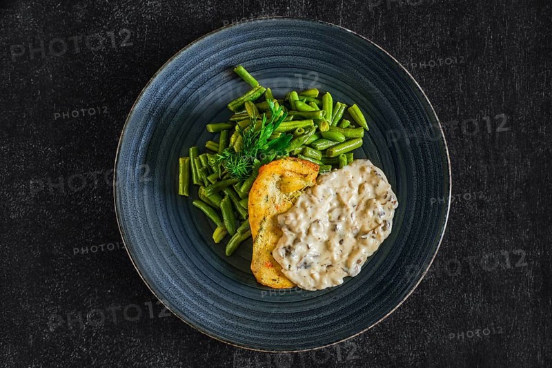 Top view of fried chicken fillet with green beans and mushroom sauce