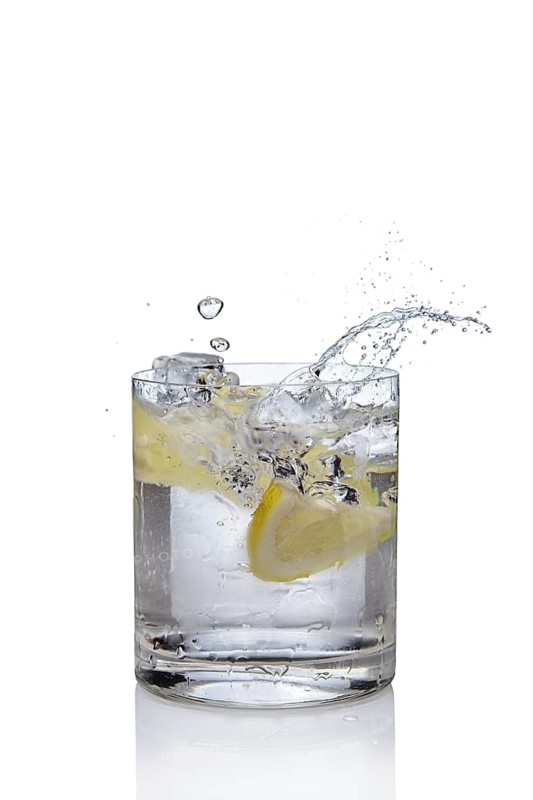 Ice cube and lemon splashing cocktail in oldfashioned glass. Drink with splashing citrus isolated on white