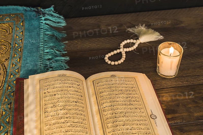 Prayer beads candle near religious book