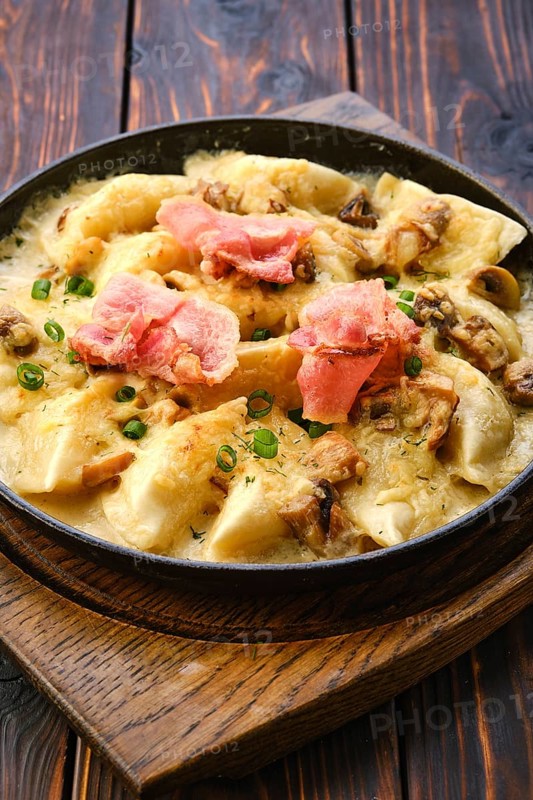 Close up view of pan with fried meat dumplings with bacon and mushroom sauce