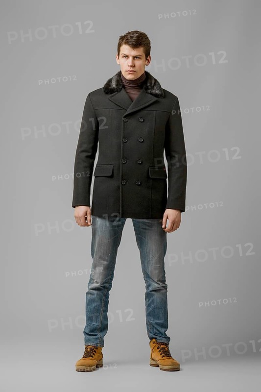 Full length portrait of handsome man in warm woolen coat posing in studio
