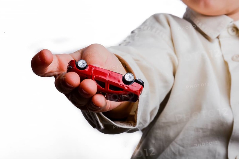 Baby hand holding a red car on a white background