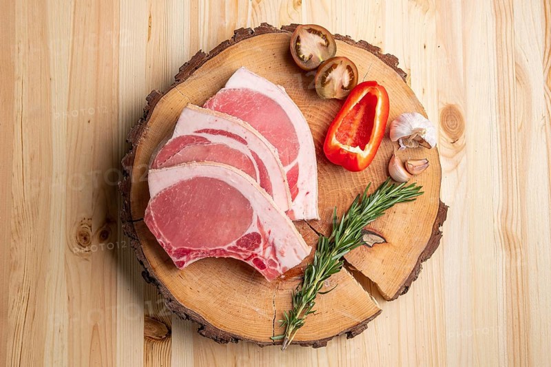 Raw fresh pork fillet steak on the bone on wooden cutting board