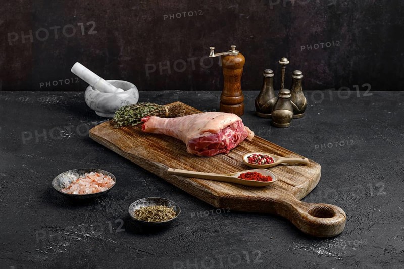 Raw turkey drumstick with skin on wooden board