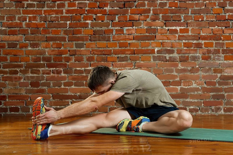 Young male cyclist athlete training and doing workout on gym mat. Fitness workout