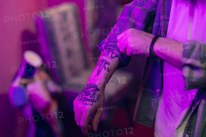 Close up man with tattoo his hand folding shirt sleeves