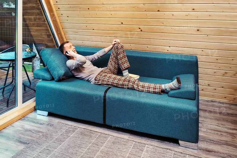 Middle aged man talking on the smartphone while resting in his forest cabin on vacations