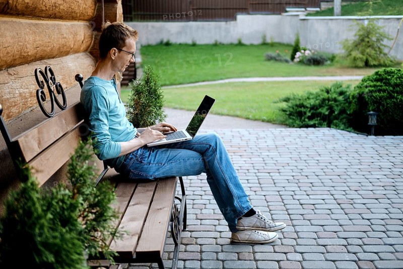 Middle aged man sitting on bench at the backyard of his country house