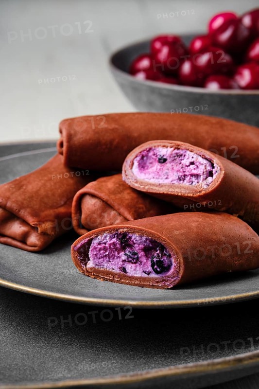 Closeup view of thin chocolate pancakes stuffed with curd