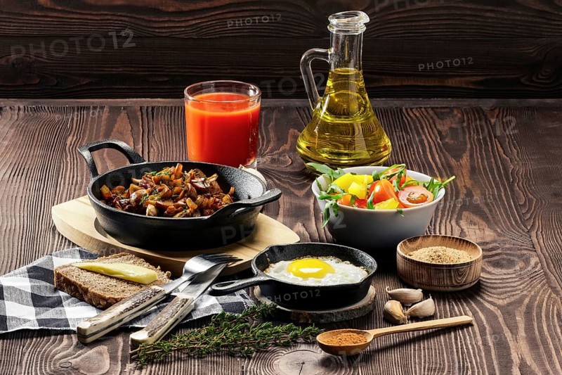 Vegetarian food. Fried mushrooms and egg in cast iron pan. Ingredients for rustic breakfast on wooden table