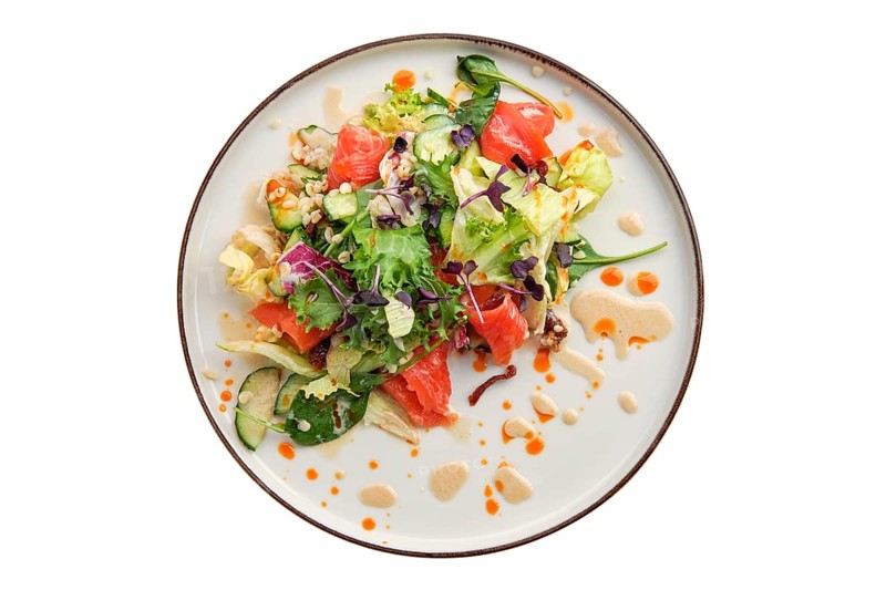 Salad with smoked salmon and fresh vegetables isolated on white background