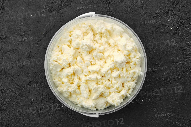 Top view of homemade cottage cheese in plastic bowl