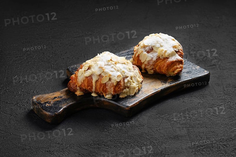 Crispy croissant with caramel and peanut shavings on wooden serving board