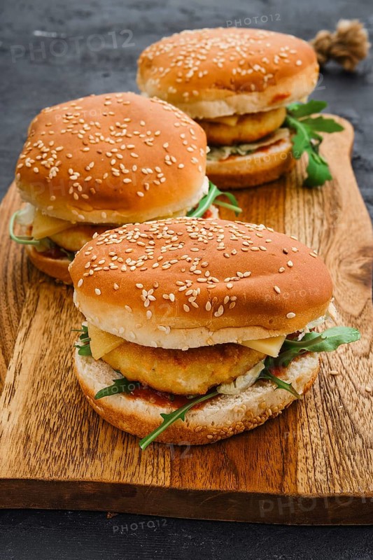 Homemade burger with chicken cutlet on long wooden board