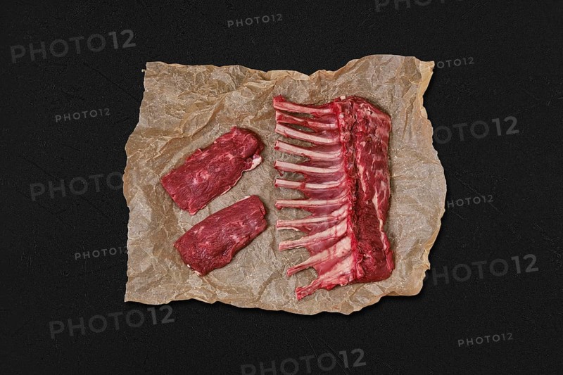 Overhead view of raw fresh rack of lamb and steak in wrapping paper