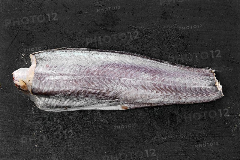 Frozen raw hake carcass on wooden table