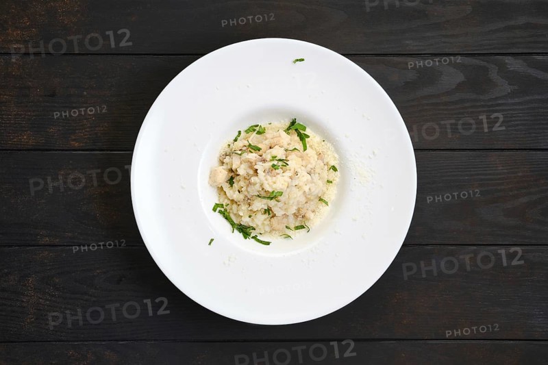 Rice with chicken pieces and grated cheese on dark wooden table