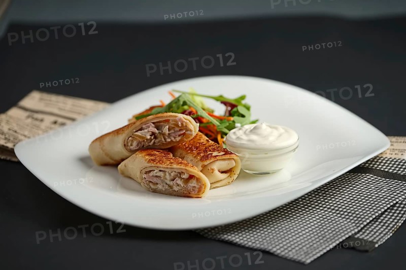 Thin flapjack stuffed with ham and cheese served with salad and sour cream