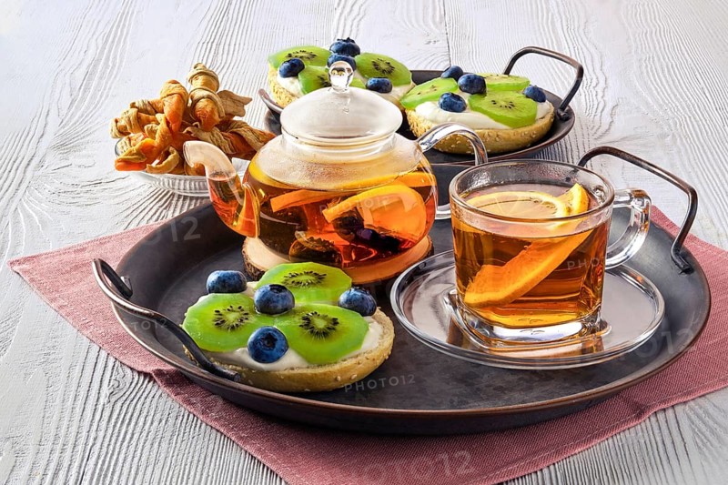 Citrus tea with cottage cheese on fresh bun with kiwi marmalade and blueberry