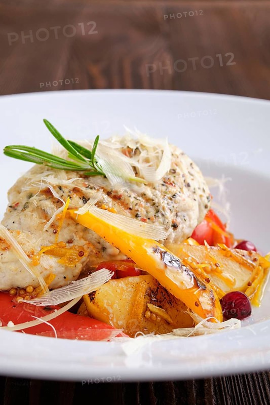 Closeup view of fried turkey meat with roasted tomato and bell pepper served with parmesan