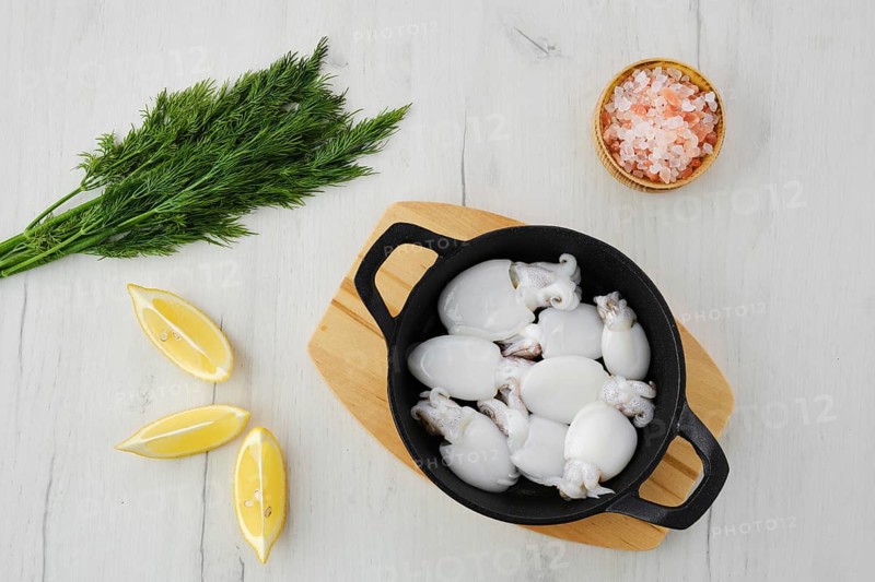 Overhead view of baby cuttlefish in cast iron skillet with dill