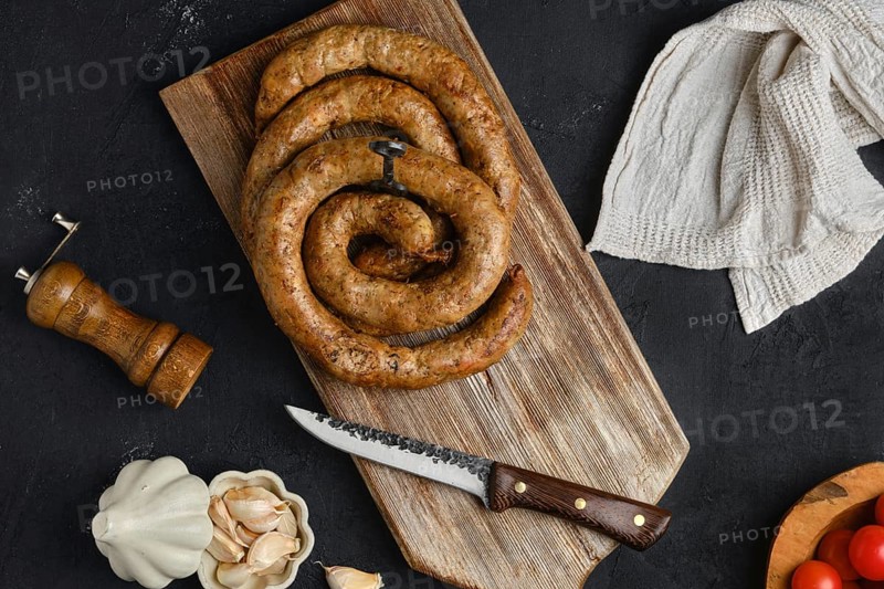 Horse meat sausage with garlic rolled on wooden cutting board