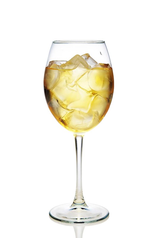 Apple cocktail with a sparkling wine with ice cubes in wine glass isolated on white