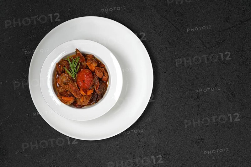 Overhead view of lamb stew with tomato on a plate