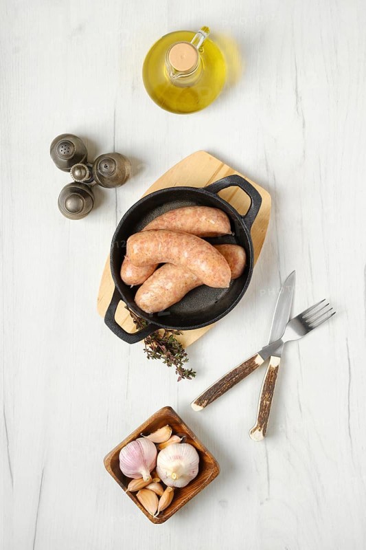 Raw traditional homemade British banger pork sausage ready for frying on wooden table