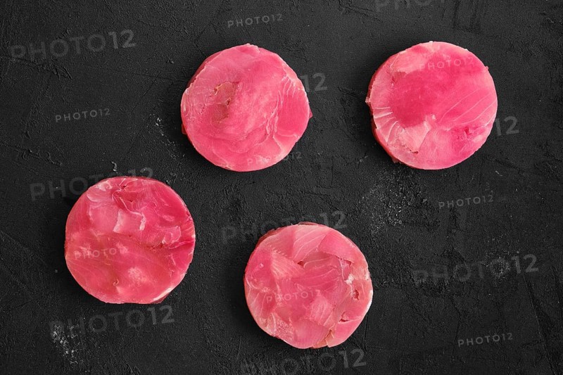 Fresh raw round tuna cutlet on wooden background