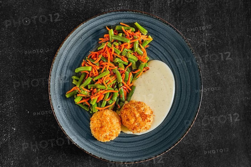 Top view of meatballs in breading served with green bean and spicy carrot