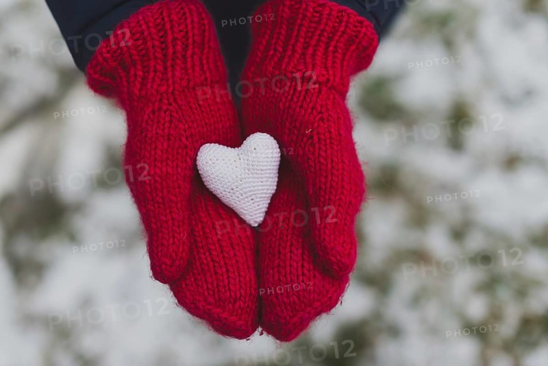 Gloved hands holding white heart