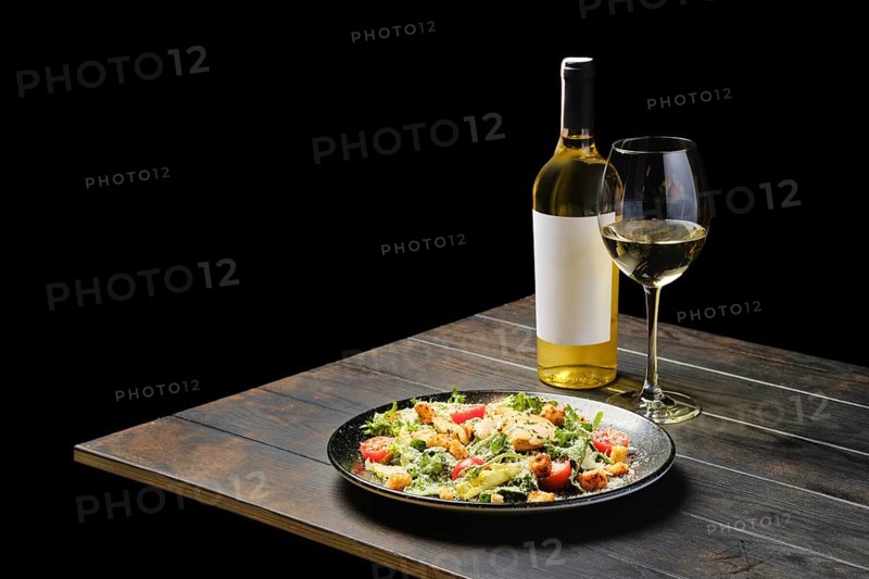 Salad with chicken and fresh vegetables with a wine on a table
