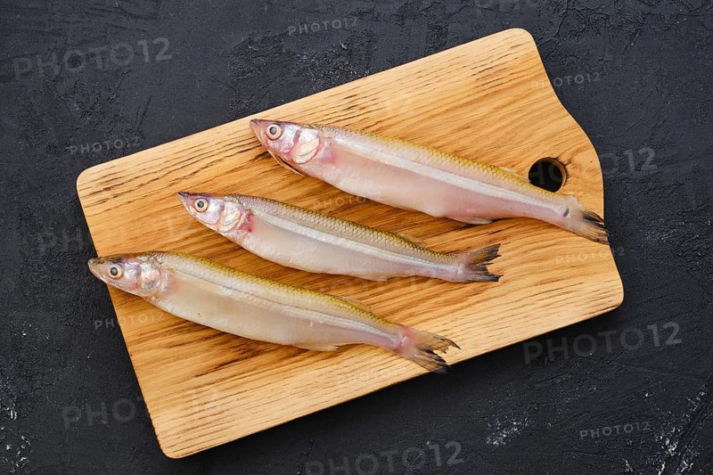 Top view of raw fresh smelt fish on wooden cutting board