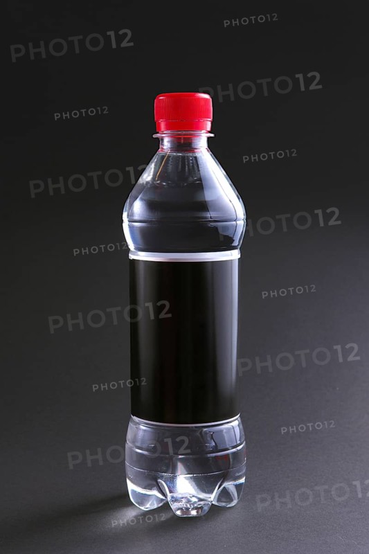 Plastic bottle of water with black label and red cap on table