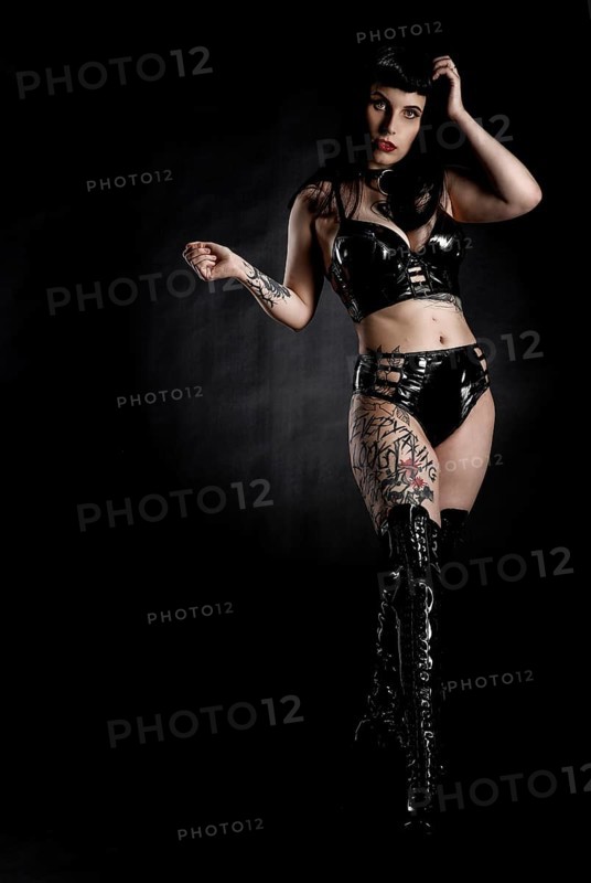 Woman with black hair and tattos in vinyl and latex outfit