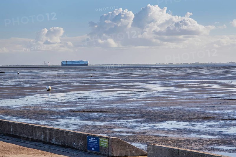 Wadden Sea on the beach promenade with car transport ship in the Weser estuary