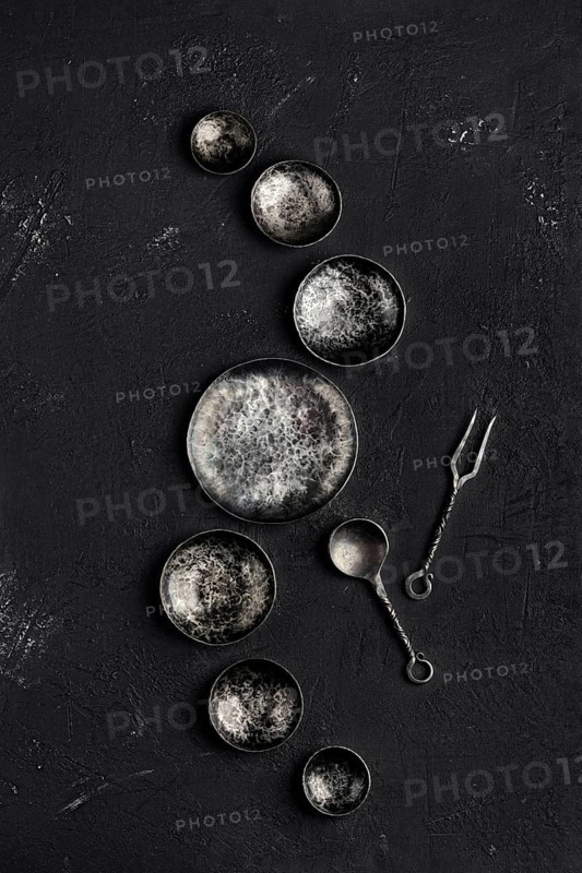 Composition with empty forged bowls of different size on black background