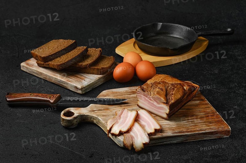 Smoked pork bacon with brown bread and eggs on wooden cutting board