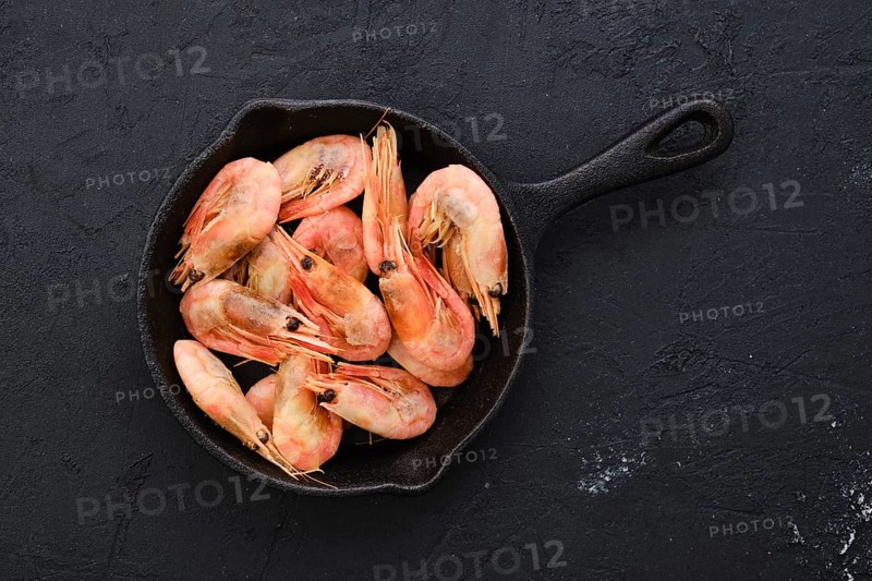 Top view of cast iron skillet with steamed unpeeled shrimps