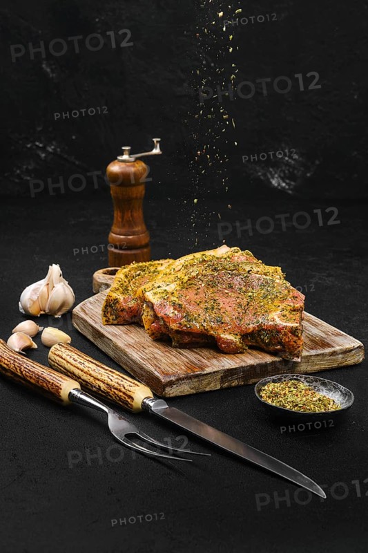 Pouring spice rub at marinated pork steak with spice ready for barbecue