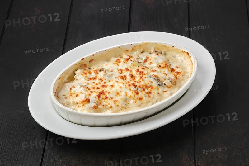 Potato and boletus casserole baked in oven with cheese and bacon