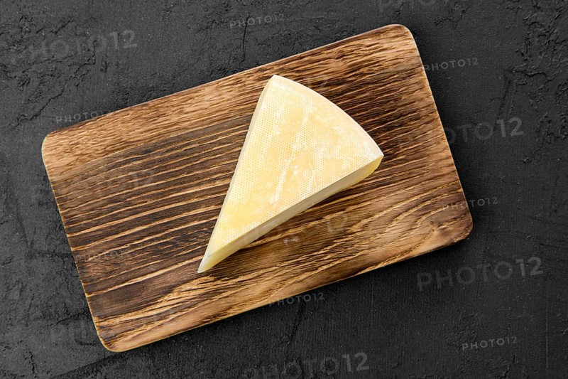 Top view of triangular piece of goat cheese on wooden cutting board