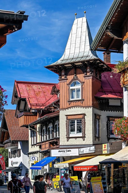 Pedestrian zone with tourists and classic wooden building with wooden shingle facade