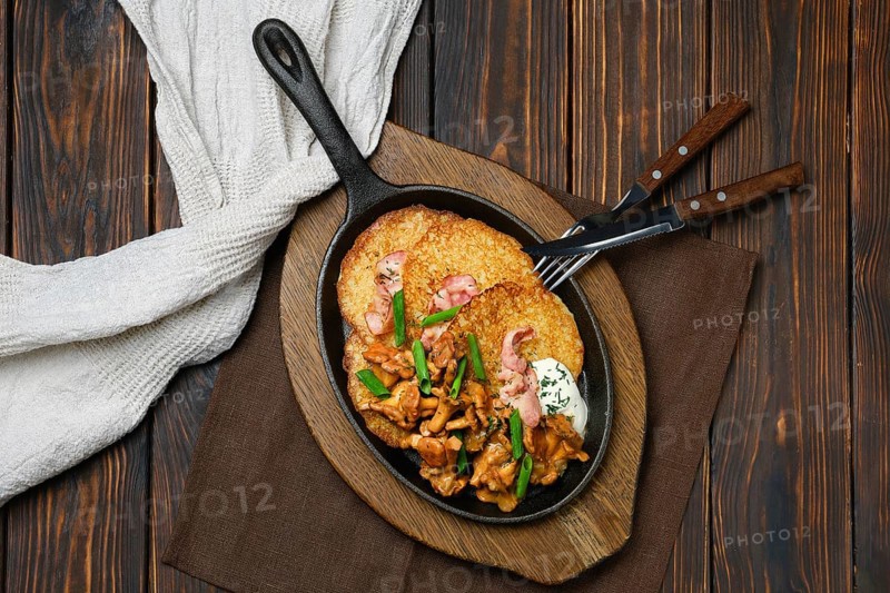 Top view of cast iron skillet with potato pancakes and fried chanterelles