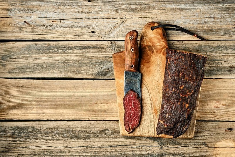 Top view of smoked dried beef meat and slice on wooden cutting board